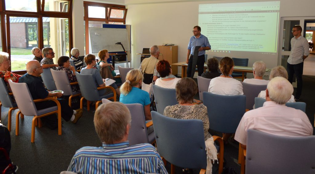 Thomas Becker, Geschäftsführer der Altus Bau GmbH zeigt unserer Wohngruppe Muster eines möglichen Fussbodenbelags, rechts vorn Jonas Gutsch, der die Sonderwünsche der Bewohner sammelt und jedem ein Angebot für die Ausstattung erarbeitet.